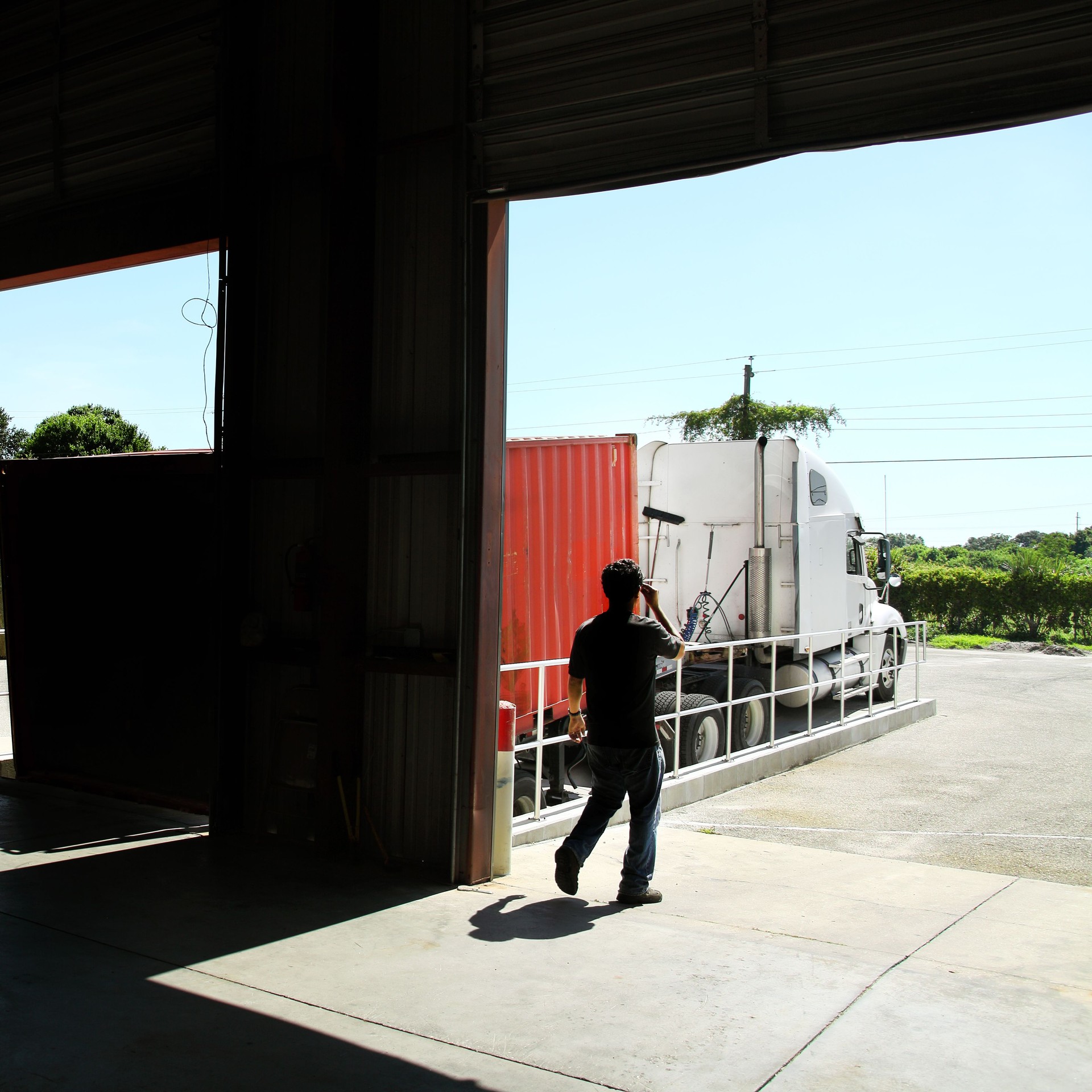 Commercial truck with cargo container parked by warehouse gate